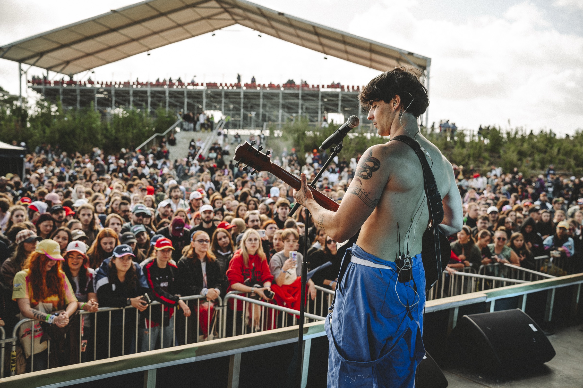 Axel Gregorcik chantant et jouant de la guitare sur scène, face au public.